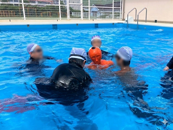 プールの中で、人形を人と見立てて、協力して救助している写真です。
