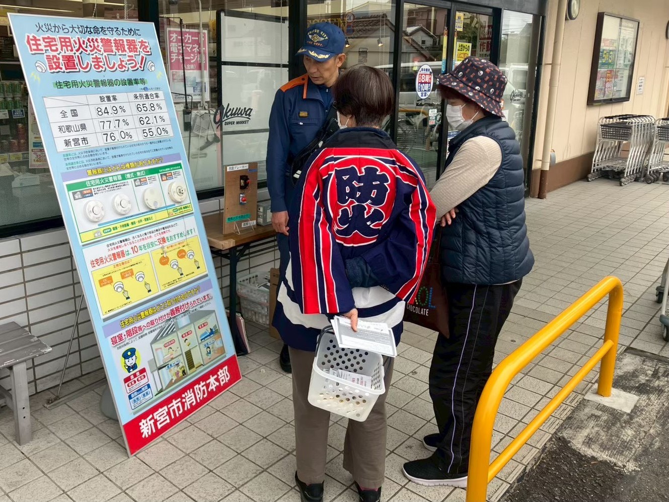 街頭啓発で住宅用火災警報器の重要性を説明している写真です。